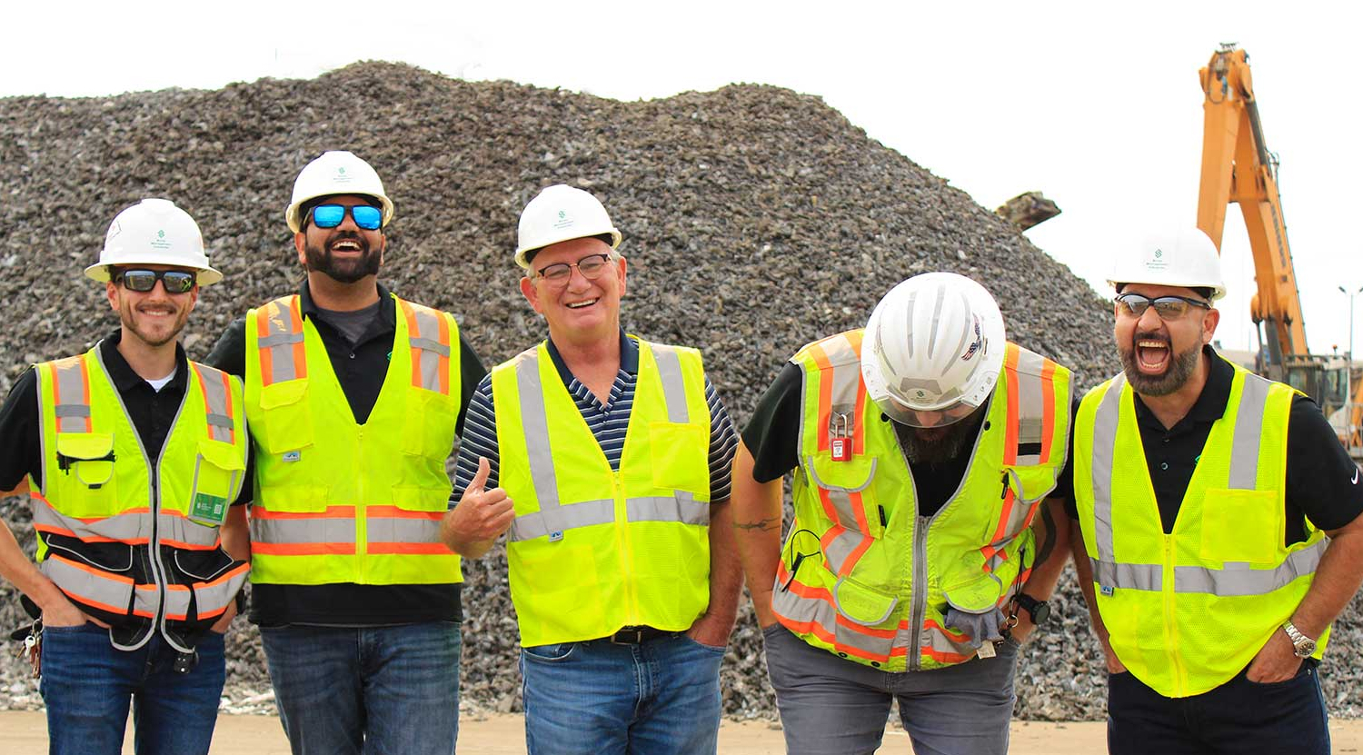 SMI workers standing in front of recycled metal